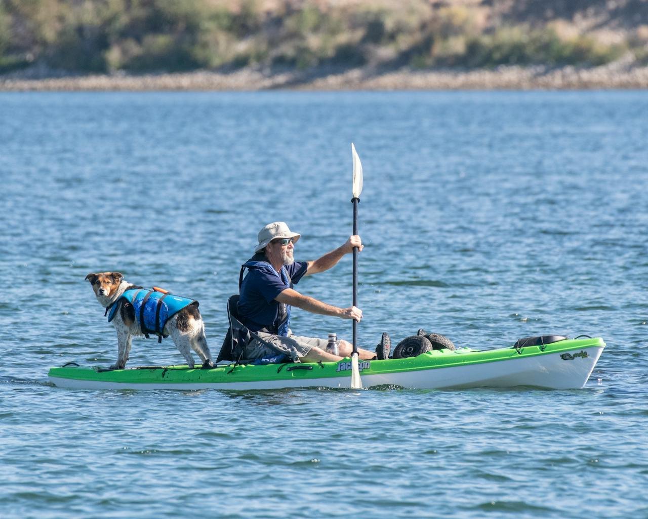 A man paddles a kayak with his dog on the Wenatchee River, enjoying a sunny day outdoors.